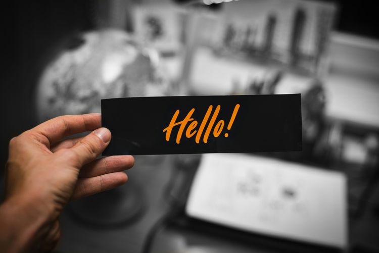 A person holding up a sticker with the word hello on it for Hello World blog post